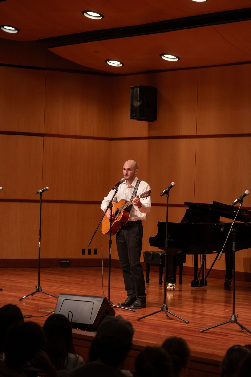 Playing acoustic guitar and singing on a concert hall stage
