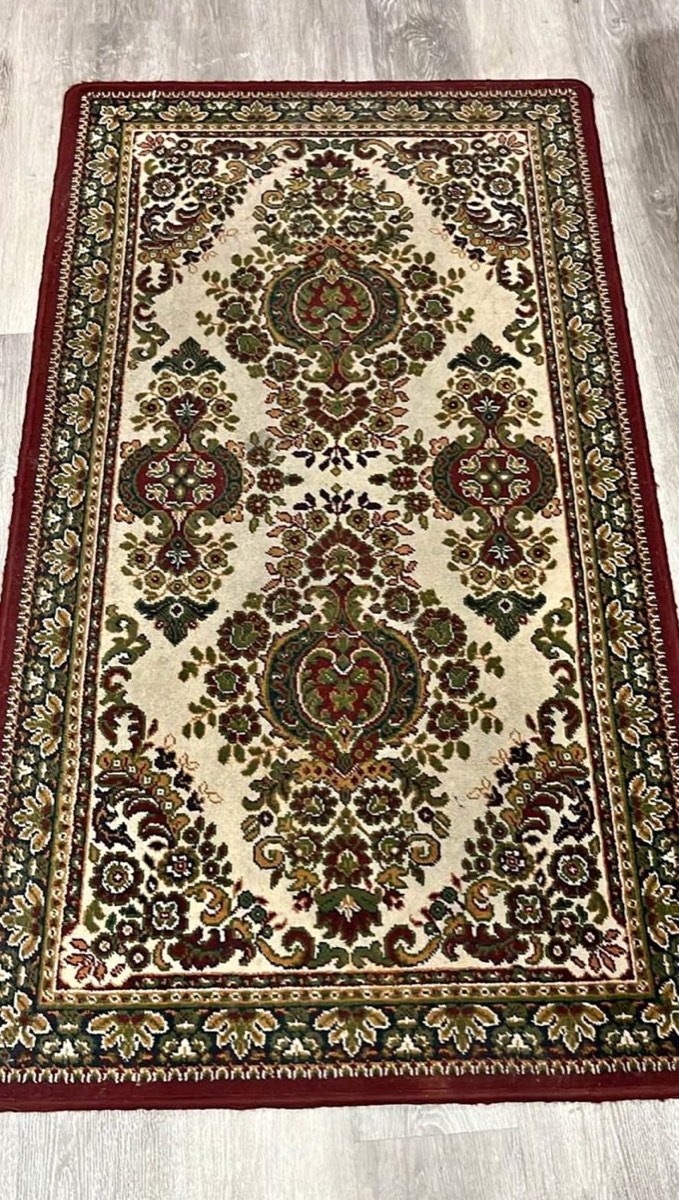 The vintage Persian-style rug before cutting: cream field, red and green florals, red border