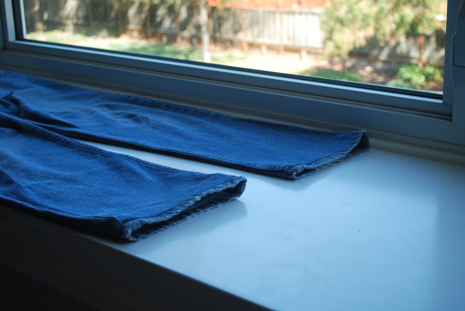 The hemmed legs of a pair of jeans on a windowsill